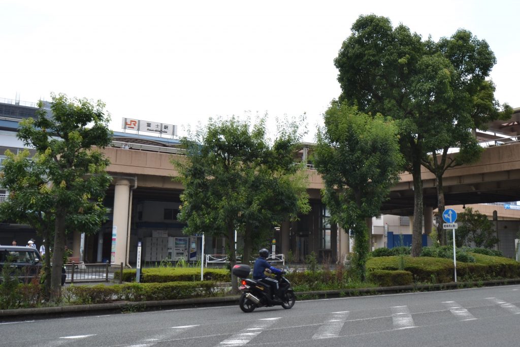 ペデストリアンデッキと街路樹に囲われる富士駅北口の駅舎