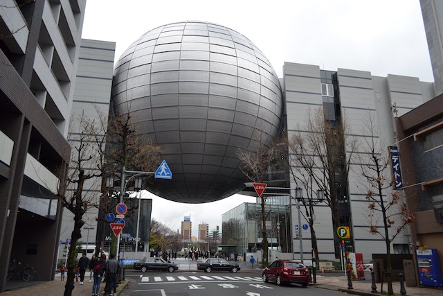 両側の建物に支えられ宙に浮いたように見える名古屋市科学館の球体天文館